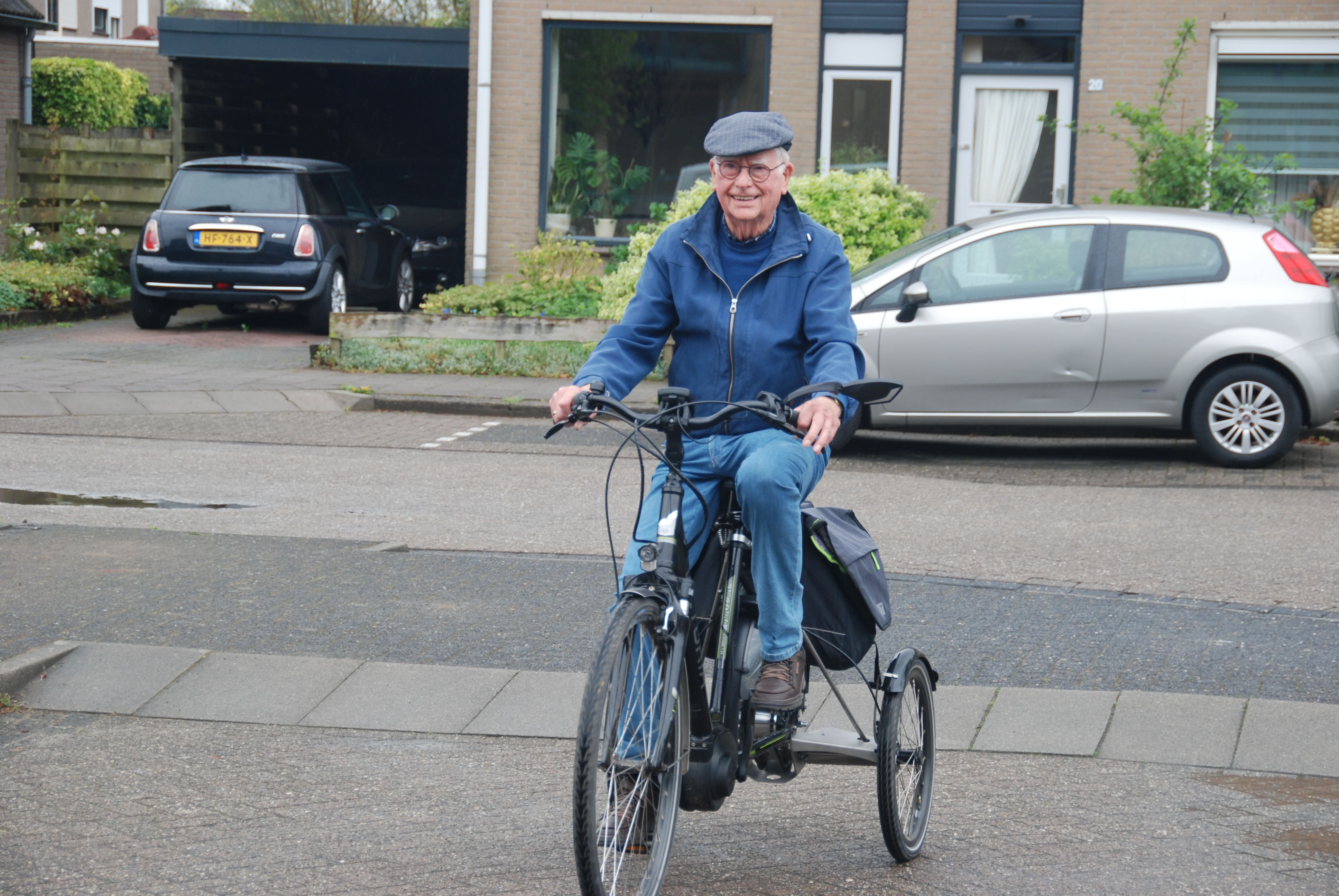 Henk (72) zit op zijn omgebouwde fiets met Tworby, klaar voor vertrek op een zonnige dag.